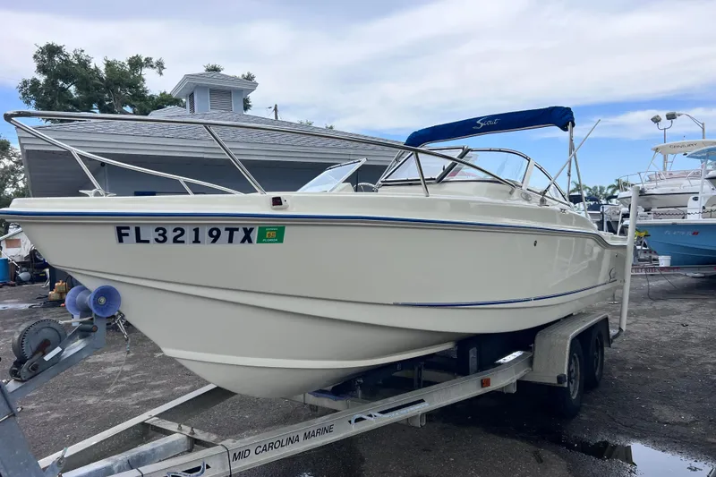 Slide: The Image of 2001 Scout 202 Dorado boat on trailer, parked outdoors near a marina. - 4
