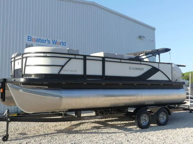 The Image of A 2026 Sweetwater SW 2086 FS pontoon boat on a trailer in front of a building. - 1
