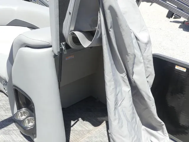 Slide: The Image of A gray boat with an open storage compartment and cover. It's a 2019 Manitou Encore 25 SR SHP. - 32