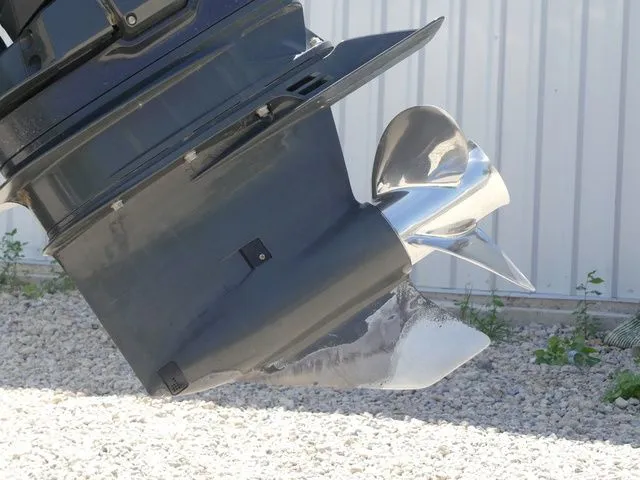 Slide: The Image of Close-up of a shiny propeller on a boat, surrounded by gravel and a metal building. - 9