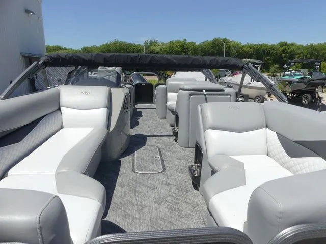 Slide: The Image of The image shows the interior of a 2019 Manitou Encore 25 SR SHP pontoon boat with gray and white seating. - 16
