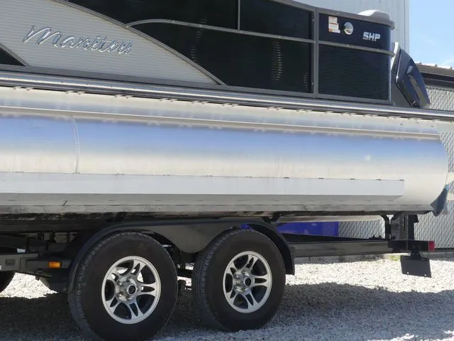 Slide: The Image of A silver pontoon boat on a trailer, with "Manitou" and "SHP" branding on the side. - 12