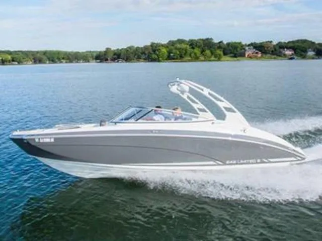 The Image of A gray Yamaha boat speeds across a calm lake, surrounded by green trees. - 1