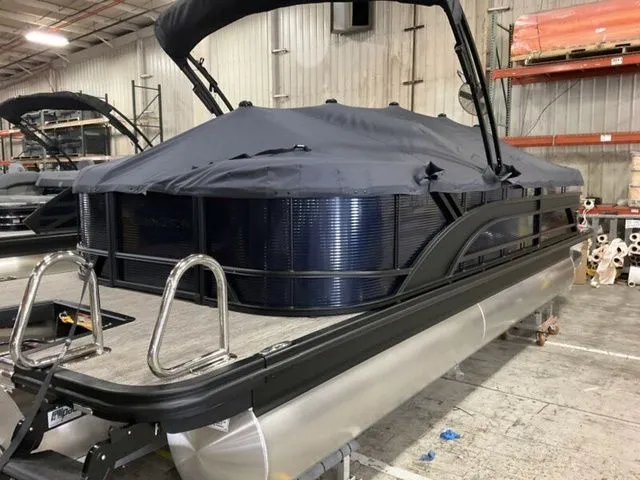 Slide: The Image of A Bennington pontoon boat with a black cover is in a warehouse. - 19