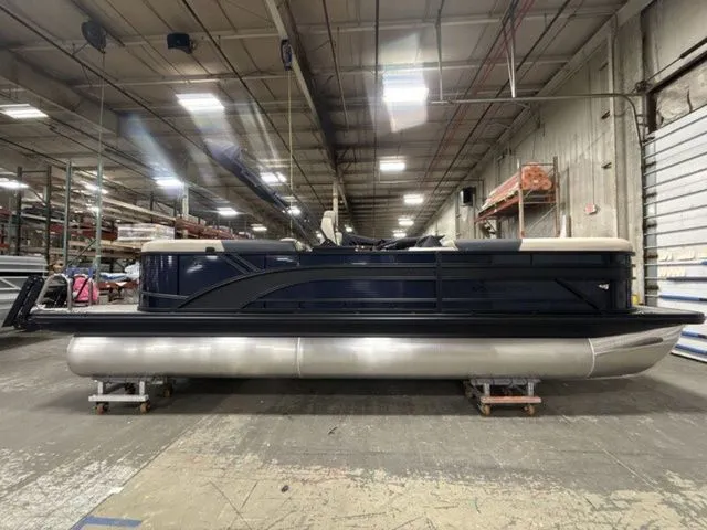 Slide: The Image of A Bennington pontoon boat is in a warehouse. It features a blue body and silver pontoons. - 9