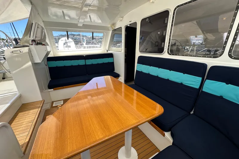 Slide: The Image of Interior of 1999 Baltec Engineering Visiona Catamaran with wooden table and cushioned seating. - 19