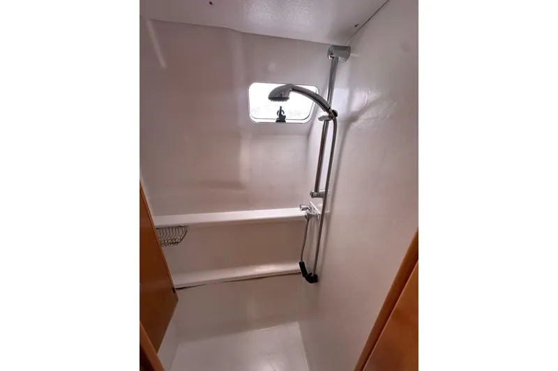 Slide: The Image of Shower area inside 1999 Baltec Engineering Visiona Catamaran, featuring a window and adjustable showerhead. - 32
