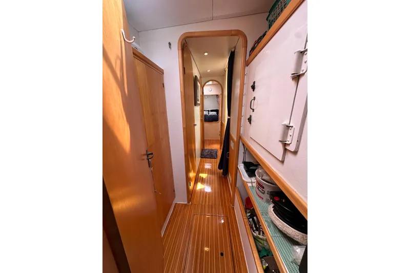Slide: The Image of Interior hallway of a 1999 Baltec Engineering Visiona Catamaran, featuring wooden flooring and storage shelves. - 51