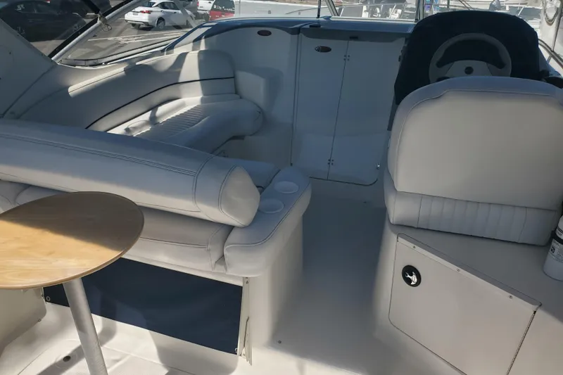 Slide: The Image of Interior of a 2004 Bayliner 285 boat with white seating and a small table. - 24