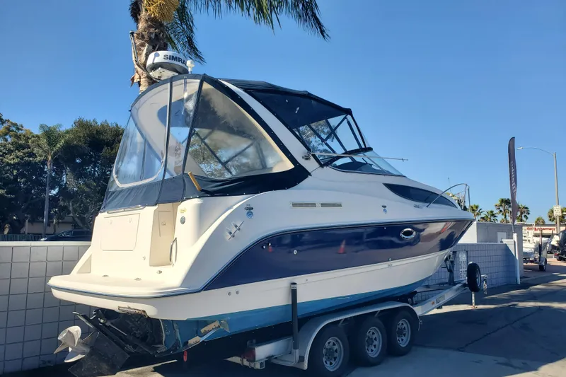 Slide: The Image of 2004 Bayliner 285 boat on trailer, parked outdoors under clear blue sky. - 2