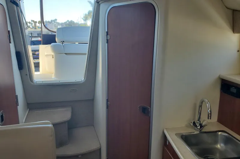 Slide: The Image of Interior view of a 2004 Bayliner 285 boat, featuring a compact kitchenette and seating area. - 9