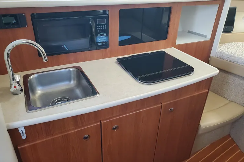 Slide: The Image of 2004 Bayliner 285 boat kitchen with sink, microwave, and stove. - 4
