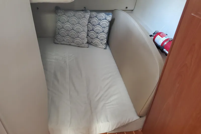 Slide: The Image of Cozy sleeping area in a 2004 Bayliner 285 boat with decorative pillows and fire extinguisher. - 11