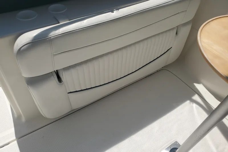 Slide: The Image of 2004 Bayliner 285 boat interior with white seating and a wooden table. - 23
