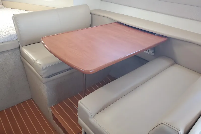 Slide: The Image of 2004 Bayliner 285 interior with beige seating and wooden table in cabin. - 5