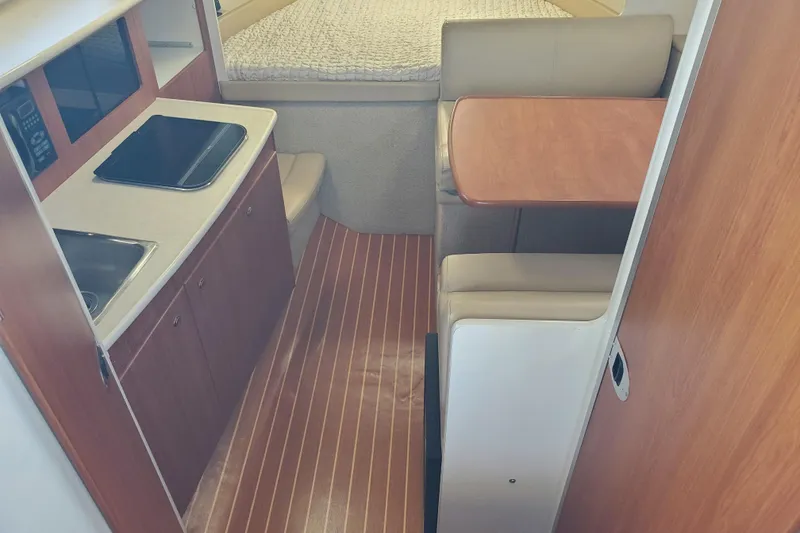 Slide: The Image of 2004 Bayliner 285 interior with kitchenette, dining area, and bed. - 3