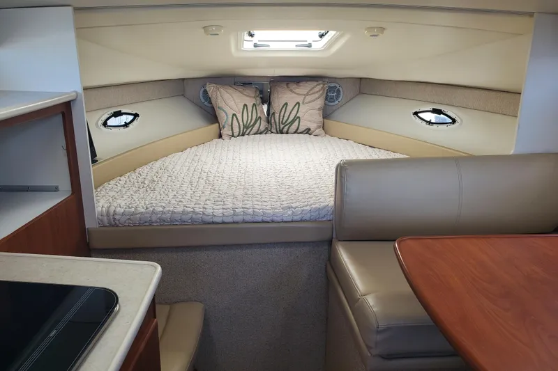 Slide: The Image of Interior of a 2004 Bayliner 285 boat featuring a cozy cabin bed and seating area. - 6