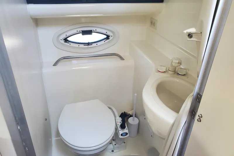 Slide: The Image of 2004 Bayliner 285 boat bathroom with toilet, sink, and porthole window. - 13