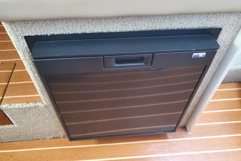 Slide: The Image of Built-in refrigerator on a 2004 Bayliner 285 boat, featuring wooden flooring. - 8