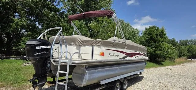 Slide: The Image of A 2008 Tracker Regency Party Barge pontoon boat on a trailer, featuring a Mercury outboard motor. - 9
