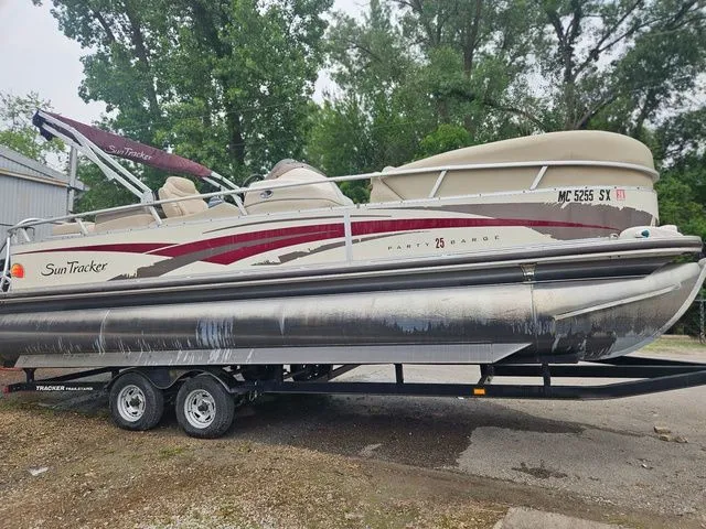 The Image of A 2008 Tracker Regency Party Barge pontoon boat on a trailer, surrounded by trees. - 1