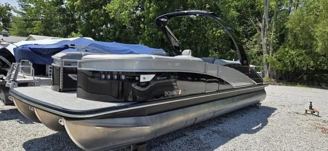 Slide: The Image of A sleek 2020 Bennington 25 RXSBA pontoon boat sits on a gravel lot, surrounded by trees. - 14