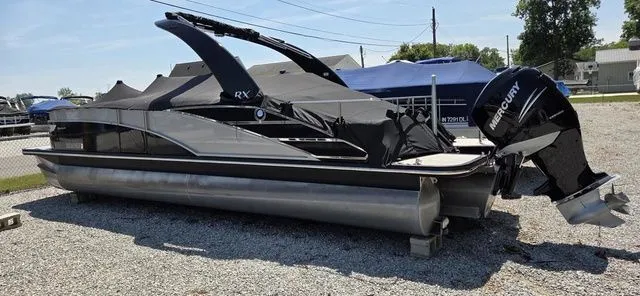 Slide: The Image of A 2020 Bennington 25 RXSBA pontoon boat with a black cover and Mercury outboard motor, on a gravel lot. - 8