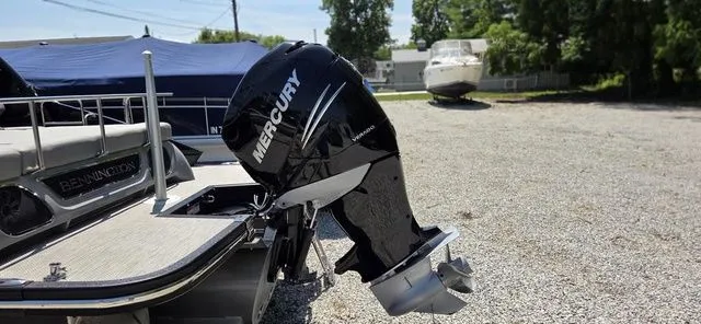 Slide: The Image of A 2020 Bennington 25 RXSBA with a Mercury outboard motor, parked on a gravel lot. - 12