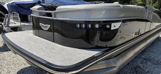 Slide: The Image of A sleek pontoon boat with a glossy black hull and silver accents, parked on a gravel lot. - 18