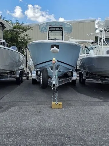 Slide: The Image of A 2027 Cobia 265CC boat on a trailer, parked between other boats in a lot. - 2