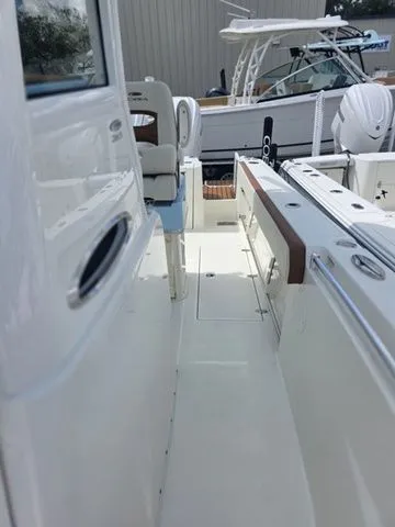 Slide: The Image of The image shows the deck of a 2027 Cobia 265CC with white surfaces and seating. - 20
