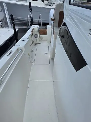 Slide: The Image of The image shows the deck of a 2027 Cobia 245CC boat with white surfaces and stainless steel railings. - 22