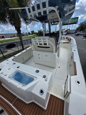 Slide: The Image of Cobia 245CC 2027: Spacious deck with seating, storage, and modern features under a blue sky. - 7