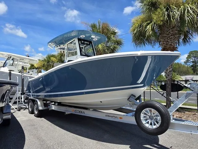 Slide: The Image of A 2027 Cobia 245CC boat on a trailer, surrounded by palm trees and blue sky. - 4