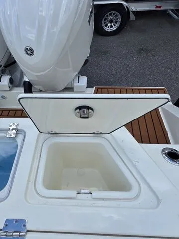 Slide: The Image of An open storage compartment on a 2027 Cobia 245CC boat, with an engine in the background. - 8
