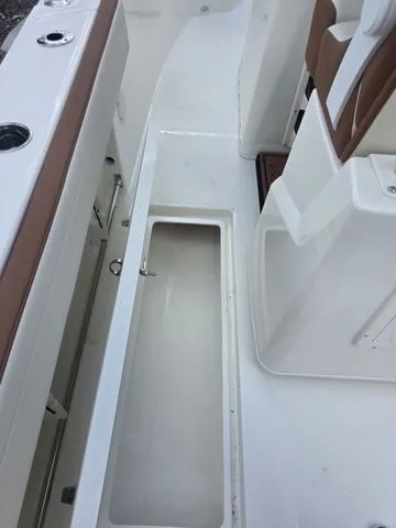 Slide: The Image of The image shows the cockpit of a 2027 Cobia 245CC with an open storage compartment. - 13