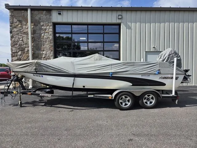 Slide: The Image of A 2003 Stratos 21 MSX boat on a trailer, covered and parked in front of a building. - 2