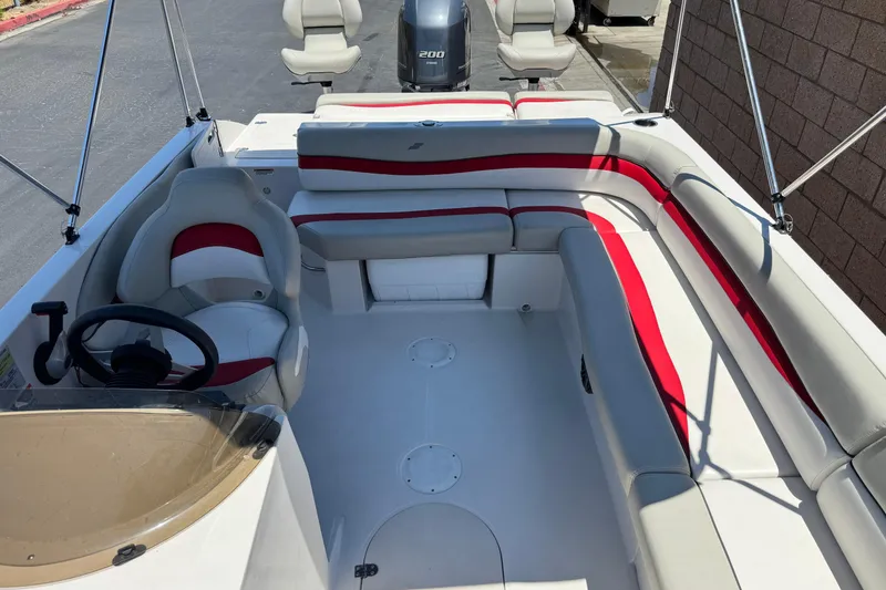 Slide: The Image of 2021 Starcraft MDX 211 O/B boat interior with red and white seating, steering wheel, and motor. - 18