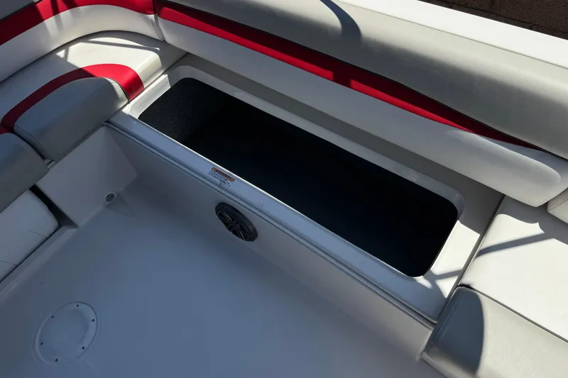 Slide: The Image of Open storage compartment on 2021 Starcraft MDX 211 O/B boat with red and gray seating. - 19