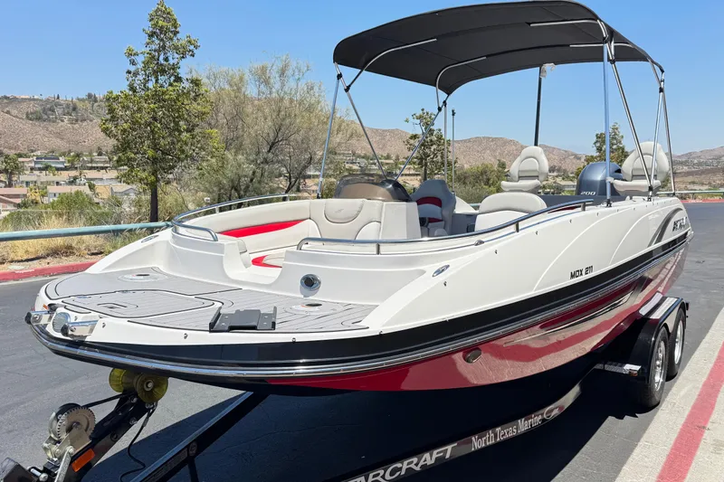 Slide: The Image of 2021 Starcraft MDX 211 O/B boat on trailer, parked outdoors under clear sky. - 3
