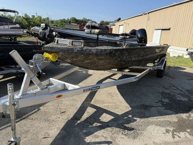 Slide: The Image of A 2026 Excel Tomahawk 183 T boat on a trailer, featuring a camouflaged hull. - 2