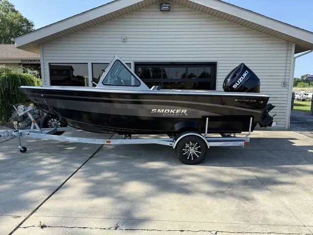 The Image of A black Smoker Craft Phantom 18 X2 boat from 2027 on a trailer in front of a building. - 1