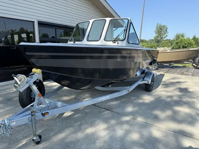 Slide: The Image of A black boat on a trailer in front of a building. It features an enclosed helm. - 2