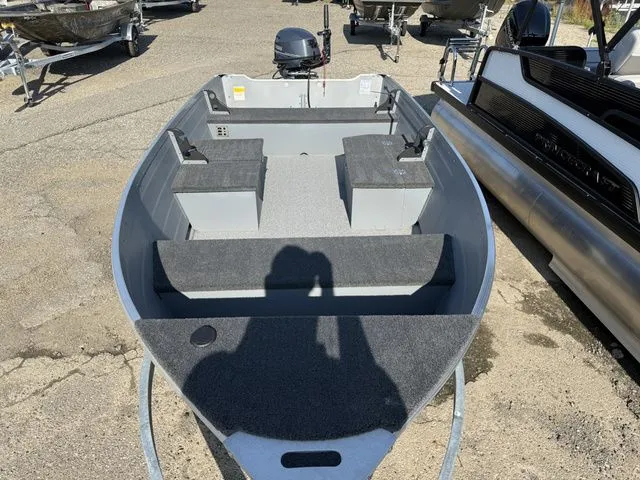 Slide: The Image of A gray aluminum boat with an open cabin and bench seating, parked on a lot. - 6