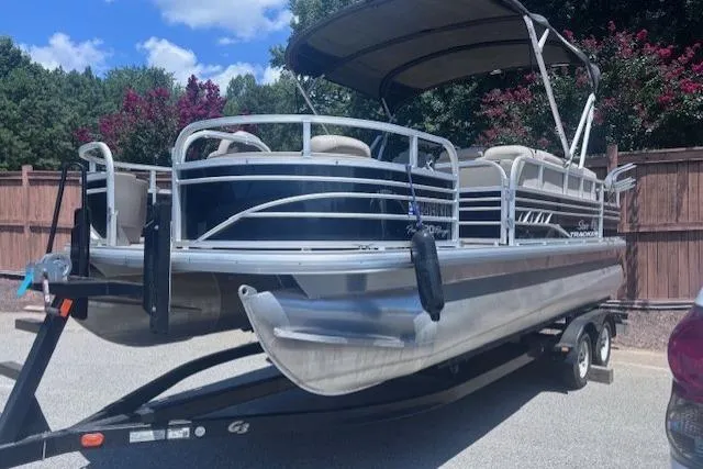 Slide: The Image of 2021 Sun Tracker Fishin' Barge 20 DLX pontoon boat on trailer, parked outdoors. - 2