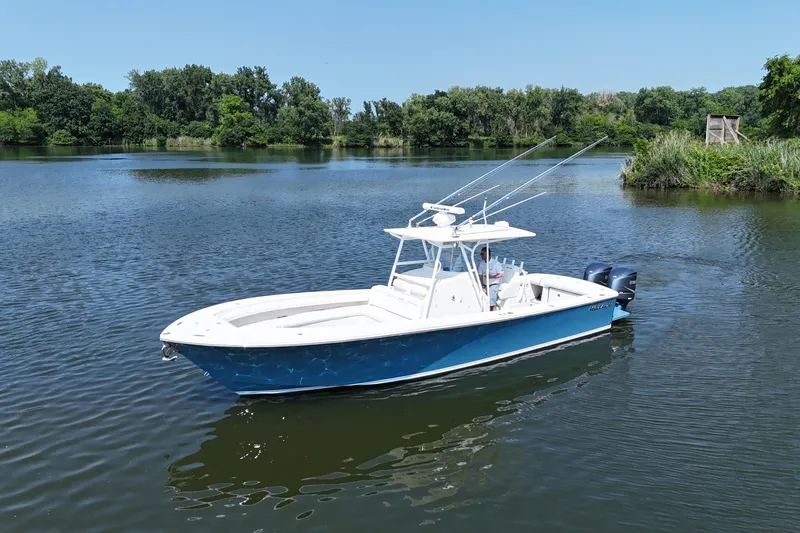 Slide: The Image of A blue and white 2010 Regulator 34SS on a calm lake with green shoreline. - 11