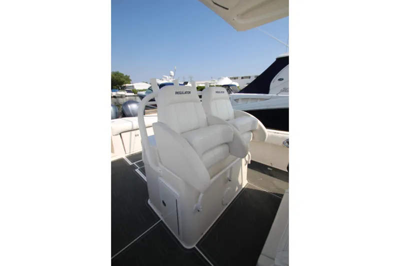 Slide: The Image of Two white, cushioned boat seats on a 2010 Regulator 34SS, with a blue sky in the background. - 26