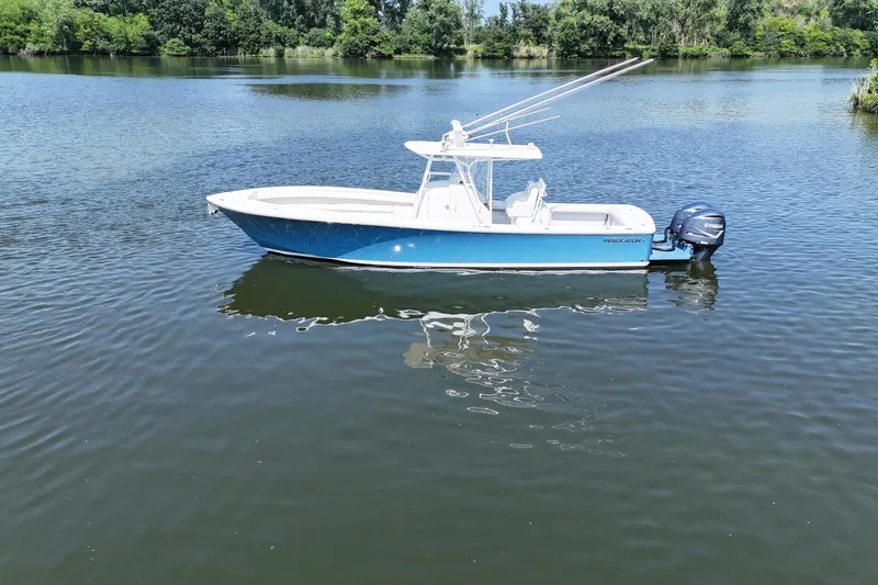 Slide: The Image of A blue and white 2010 Regulator 34SS floats on a calm lake, surrounded by trees. - 1