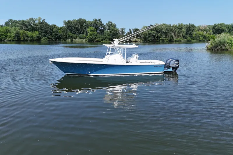 Slide: The Image of A blue and white 2010 Regulator 34SS floats on a calm lake, surrounded by trees. - 2