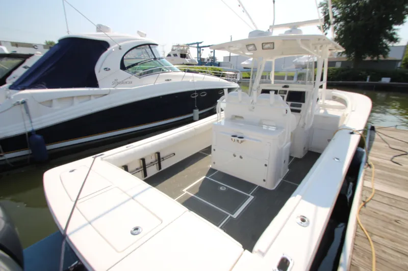 Slide: The Image of A 2010 Regulator 34SS boat docked. It features a spacious deck and a central helm console. - 22
